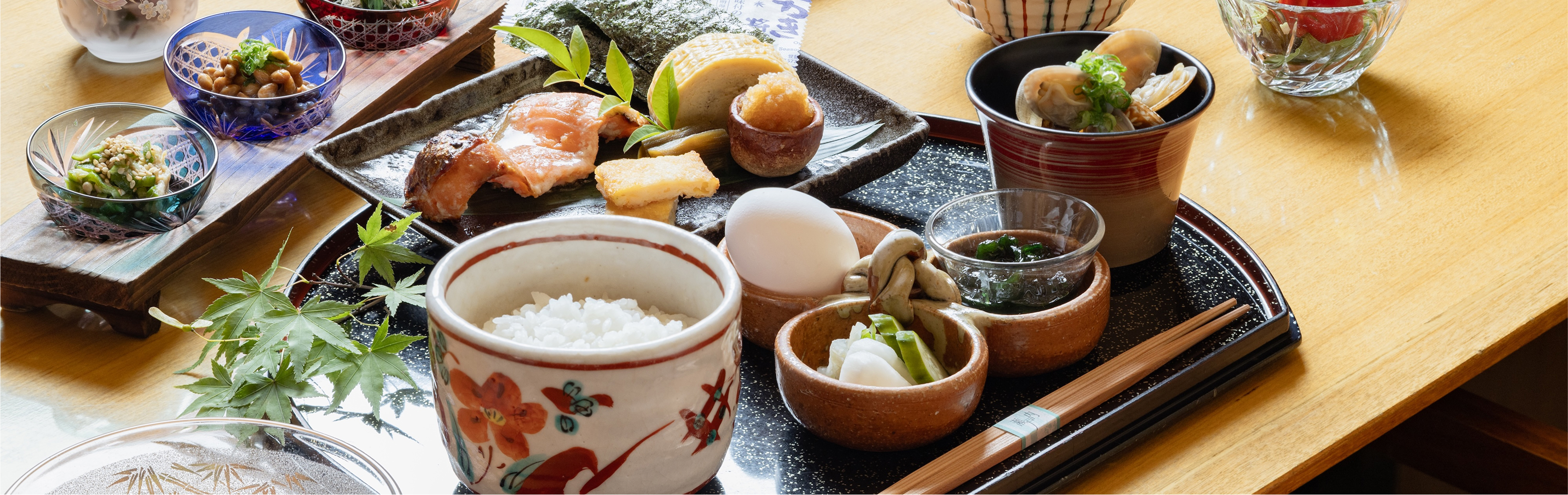 焼き魚や出汁巻き卵、炊きたてご飯、生卵、小鉢が並ぶ彩り豊かな和朝食の膳