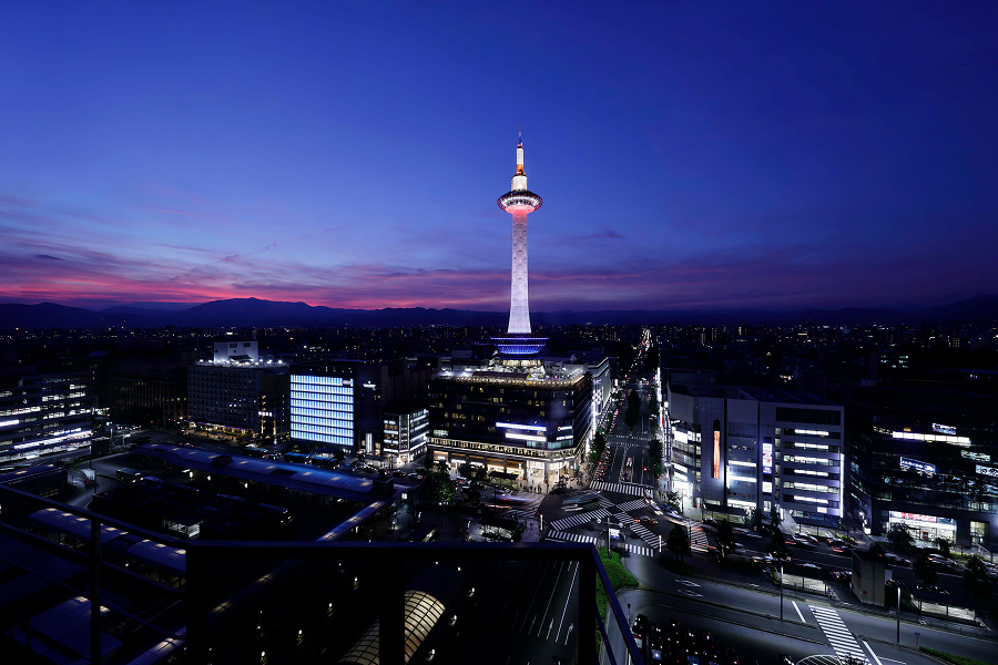 Kyoto Tower soaring against the sunset sky, with a distant view of the city.