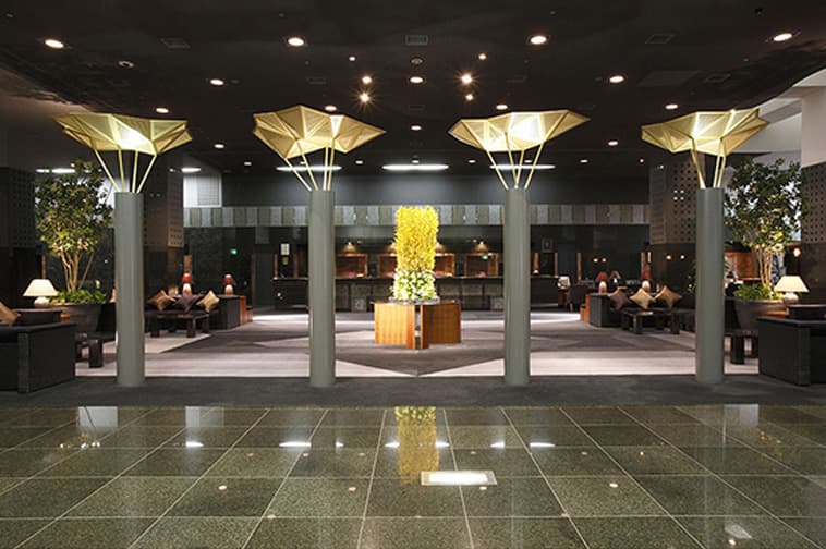 The interior of the spacious hotel entrance lobby, featuring striking ceiling lighting.