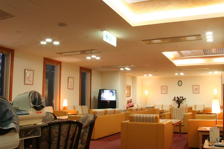 A bright clinic waiting room furnished with sofas and a reception counter.
