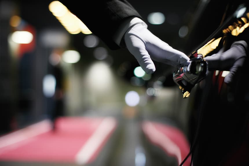Hotel valet parking. A staff member wearing white gloves is opening the car door.