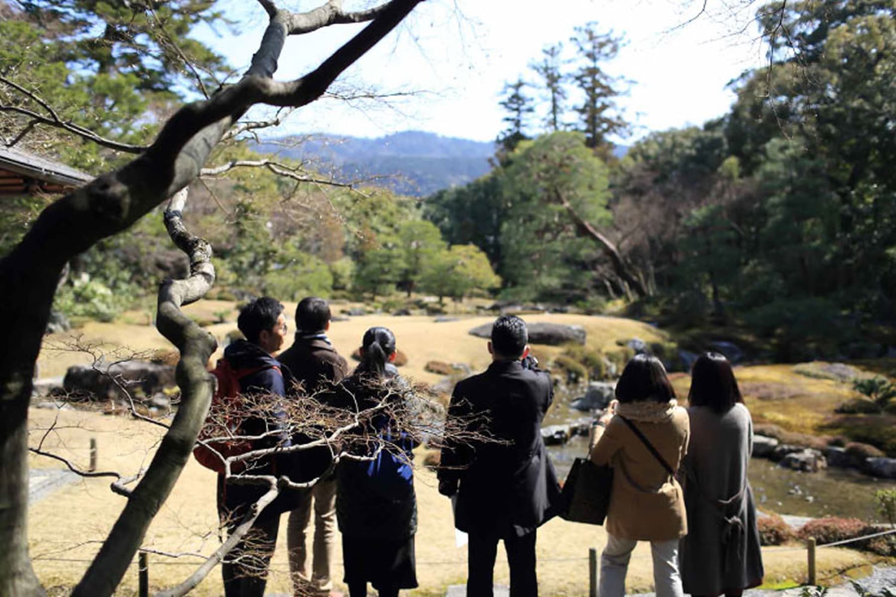 広大な日本庭園の風景を眺める観光客（複数人）