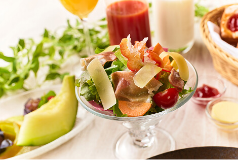 A salad made with prosciutto and various vegetables such as lettuce and tomatoes.