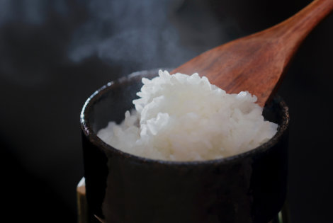 A bowl of white rice is served, and several small plates are lined with pickles and dried sardine side dishes.