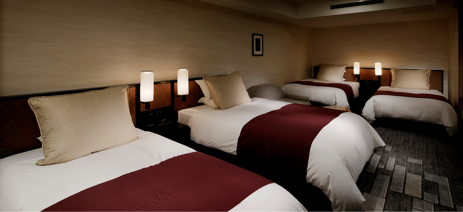 Granvia Family Room features four beds, two on each side, and boasts a calming atmosphere with its dark wood grain and warm lighting.
