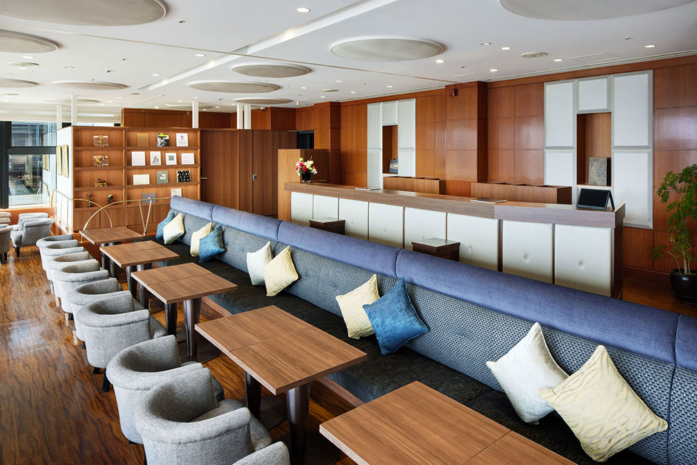 Lounge features wood-grain desks and blue and white cushions, creating a calm and relaxing atmosphere with its rows of sofa and table seating.