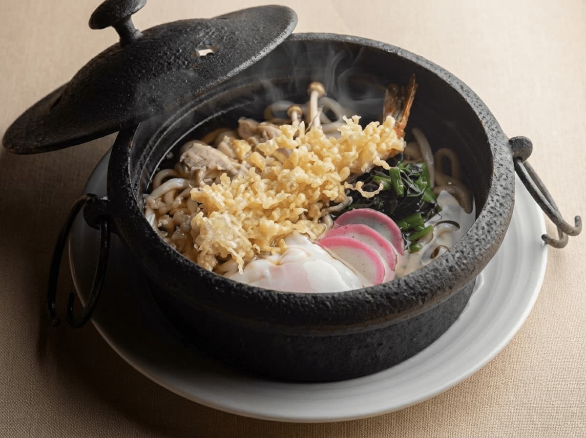 Udon noodles served in a black earthenware pot with a lid