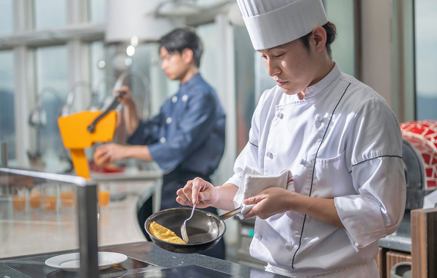 窓からの眺めが見える、棚に本や小物が飾られた落ち着いた雰囲気のラウンジ。