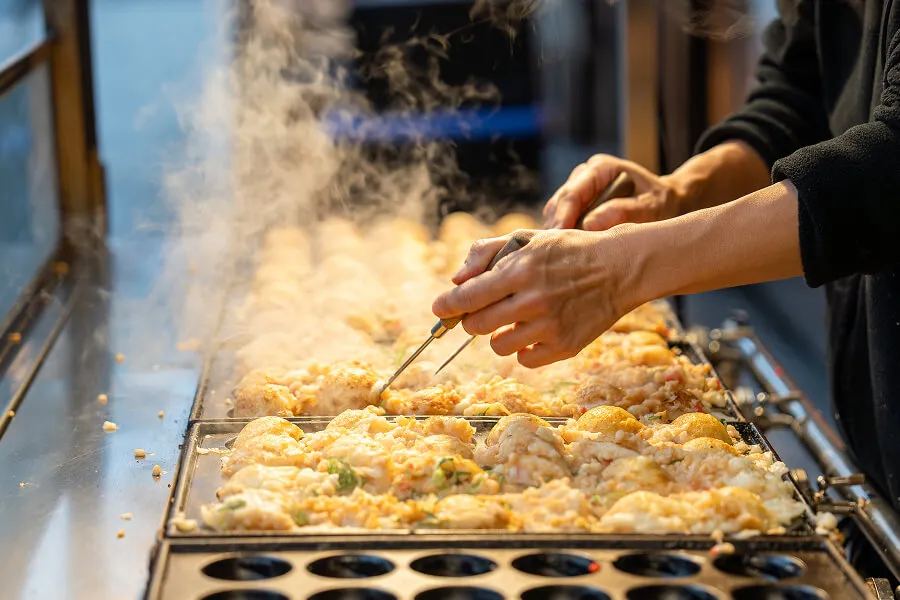 鉄板で焼かれる熱々のたこ焼きを作る様子