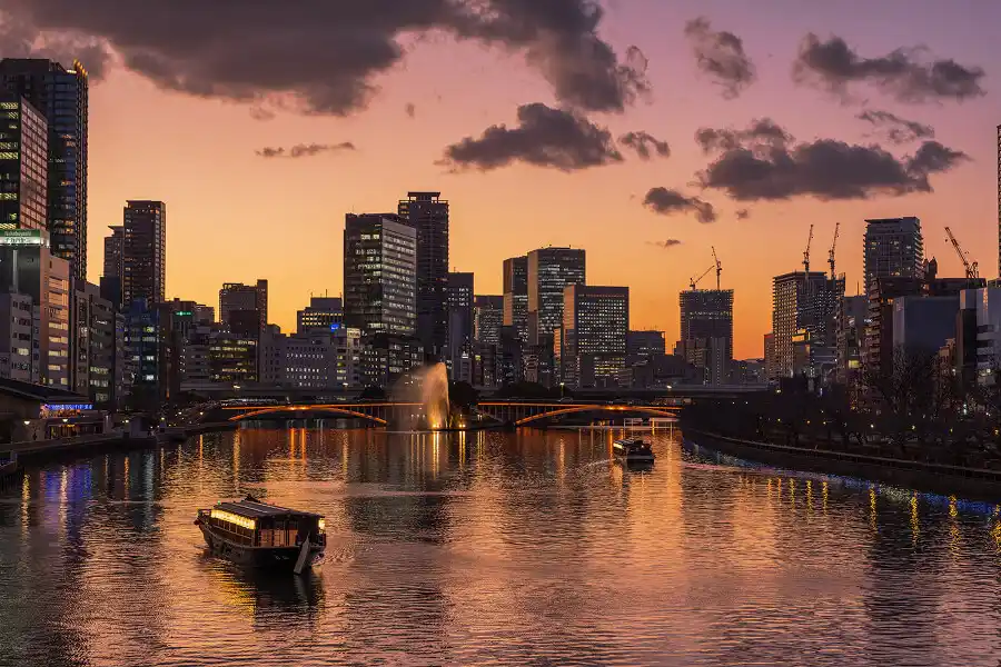 夕暮れの川を進む観光船と都市の景色