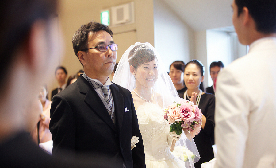 父親にエスコートされた花嫁が、新郎のもとへゆっくりと歩みを進めています。