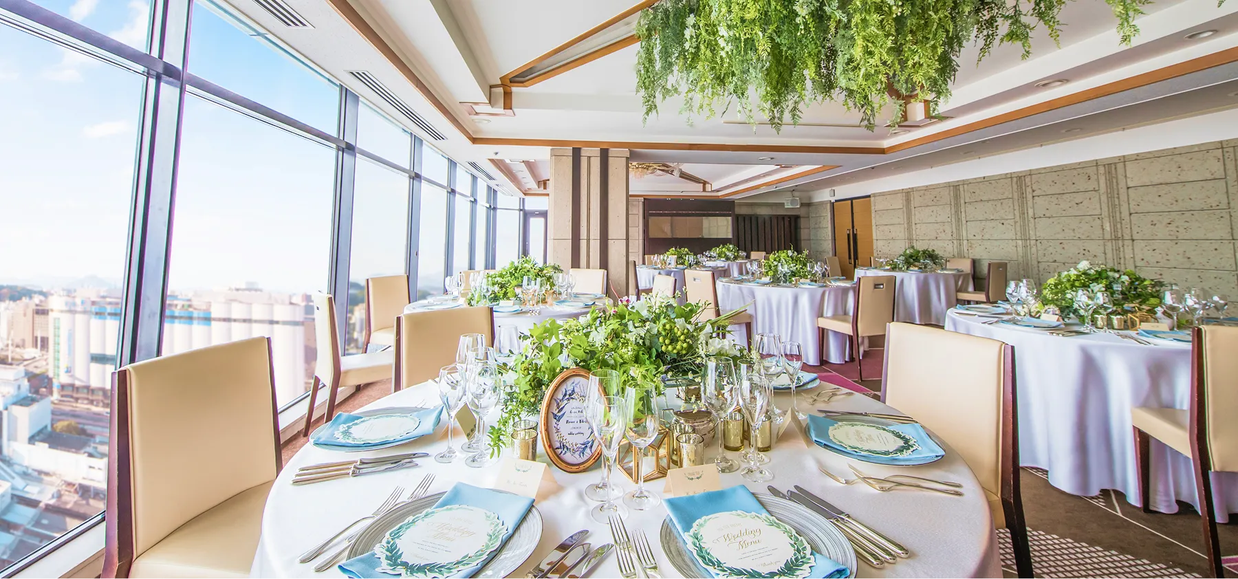 紫色の装飾が施されたテーブルが並ぶ、広々とした結婚披露宴会場です。