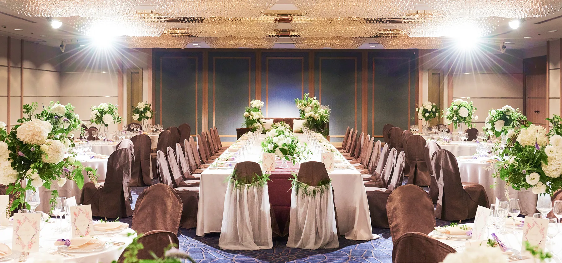 紫色の装飾が施されたテーブルが並ぶ、広々とした結婚披露宴会場です。