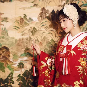 金屏風の前で扇子を手に佇む、華やかな色打掛姿の花嫁