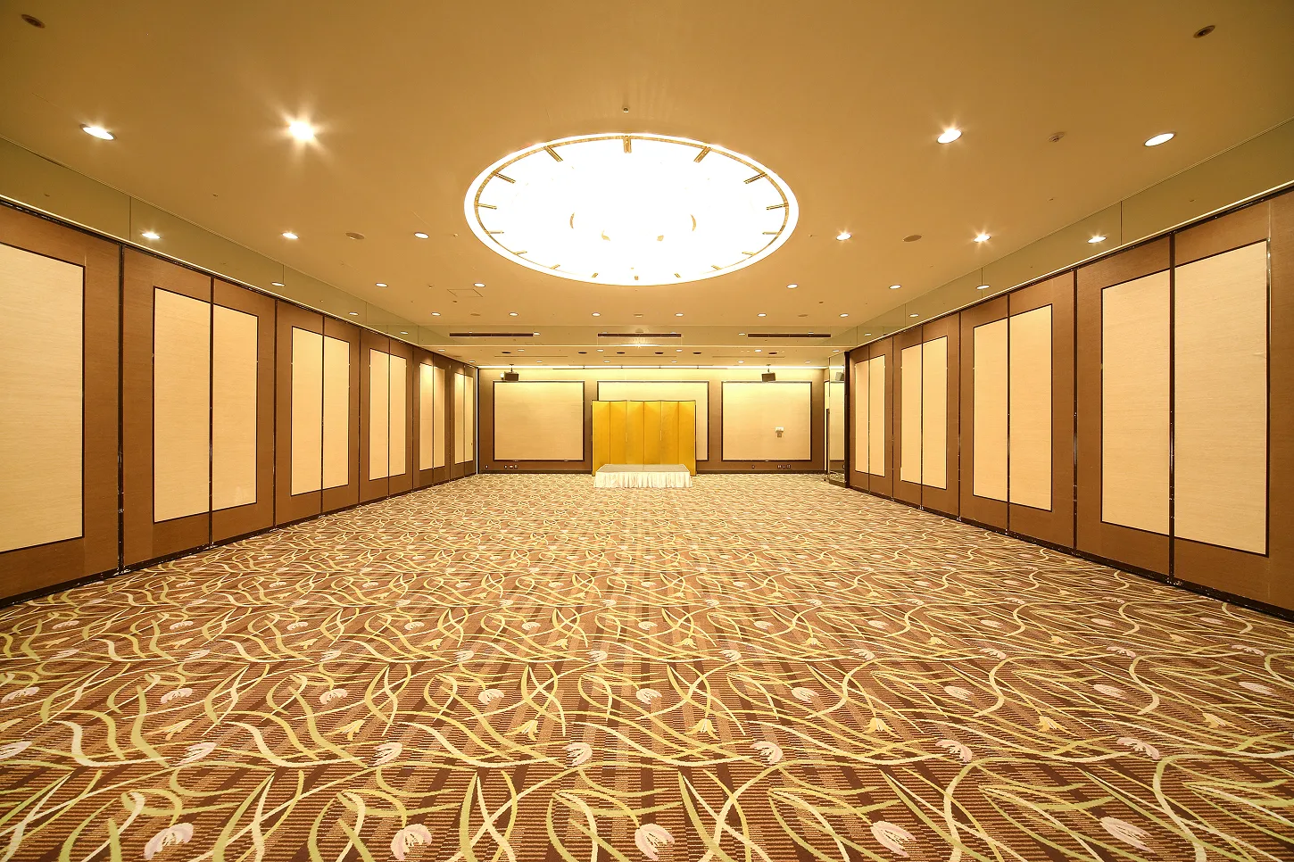 幾何学的な模様の絨毯が敷き詰められた、広大で豪華な宴会場の全景