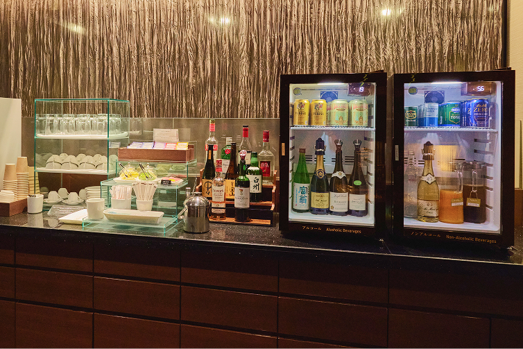 厳選されたアルコールや飲料が並ぶ冷蔵庫とグラス類が整然と配置されています。