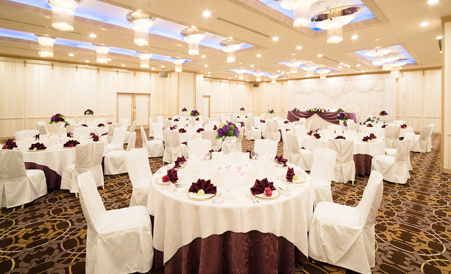 紫色の装飾が施されたテーブルが並ぶ、広々とした結婚披露宴会場です。