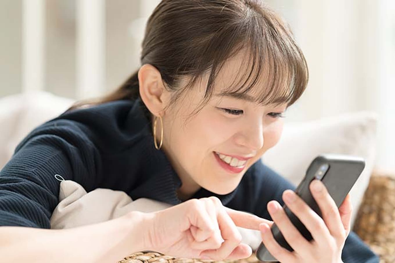 笑顔でスマートフォンを操作する女性。