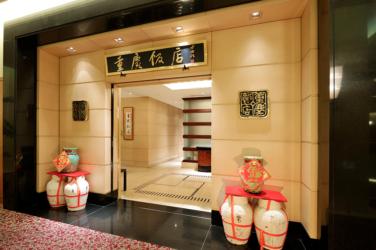 黒い大理石のフレームに金色の文字で「重慶飯店」と掲げられた、格式高いエントランス。入り口の両脇には赤い飾りのついた伝統的な大きな甕（かめ）が置かれている。
