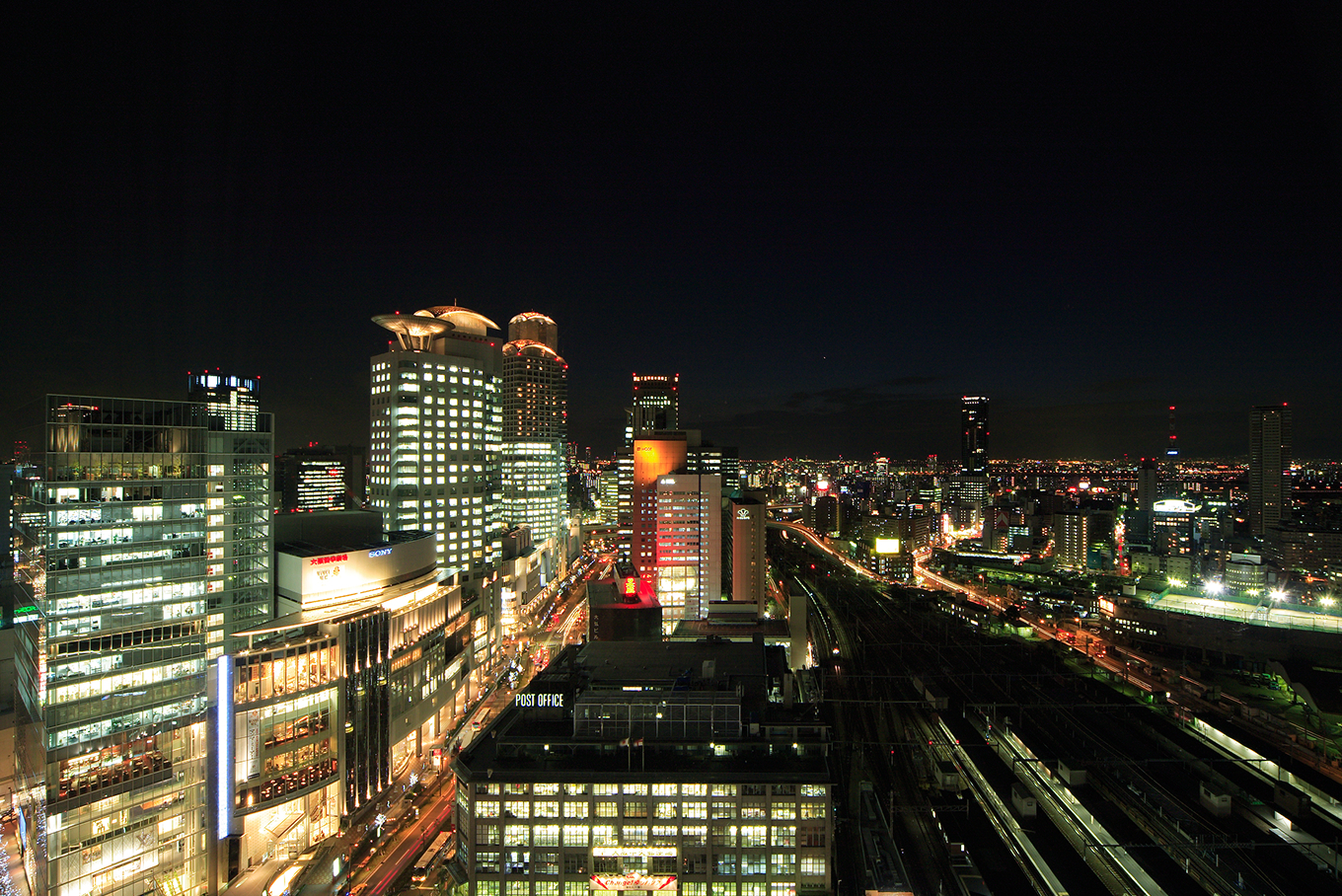 夜景が見える窓際の椅子、木目調の壁が特徴の、ツインベッドが置かれた高級感のあるホテルの客室。