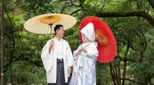 和傘を差して和装を着て見つめ合う新郎新婦