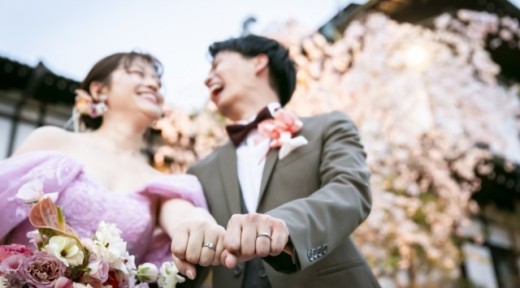 桜の前で笑い合う新郎新婦　ピンクのカラードレス