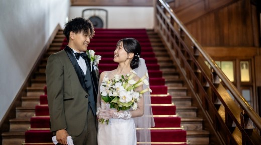 大階段で洋装を着て見つめ合う新郎新婦