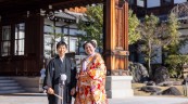 正面玄関前を背景に笑顔の紋付袴の新郎と色打掛の新婦