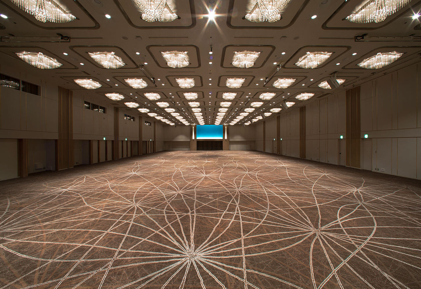 幾何学的な模様の絨毯が敷き詰められた、広大で豪華な宴会場の全景