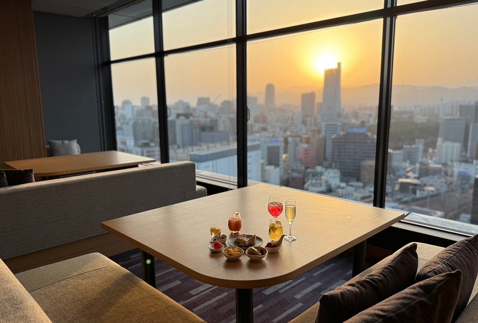 夕暮れを背景にテーブルを彩るカクテルとおつまみ