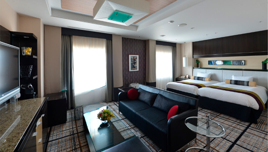 ベッド奥にソファとローテーブルを備えたリビング付き客室