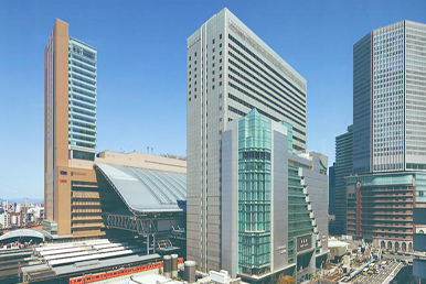 青空の下で高層ビルが立ち並ぶ都市の風景が広がっています。