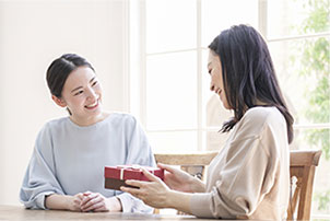 圖:一位女士向旁邊的女士贈送禮物