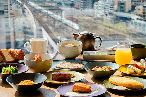 最上階の窓際テーブルに並ぶグランヴィアラウンジの朝食。オムレツや魚料理、パン、サラダなどの多彩な料理。