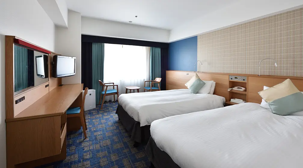 木目調の壁と青いクッションが印象的な高級感のあるツインルーム