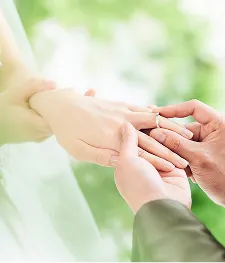 新郎が新婦の左手薬指に結婚指輪をはめるシーン