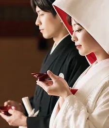 三三九度の盃を手にする白無垢姿の花嫁と新郎