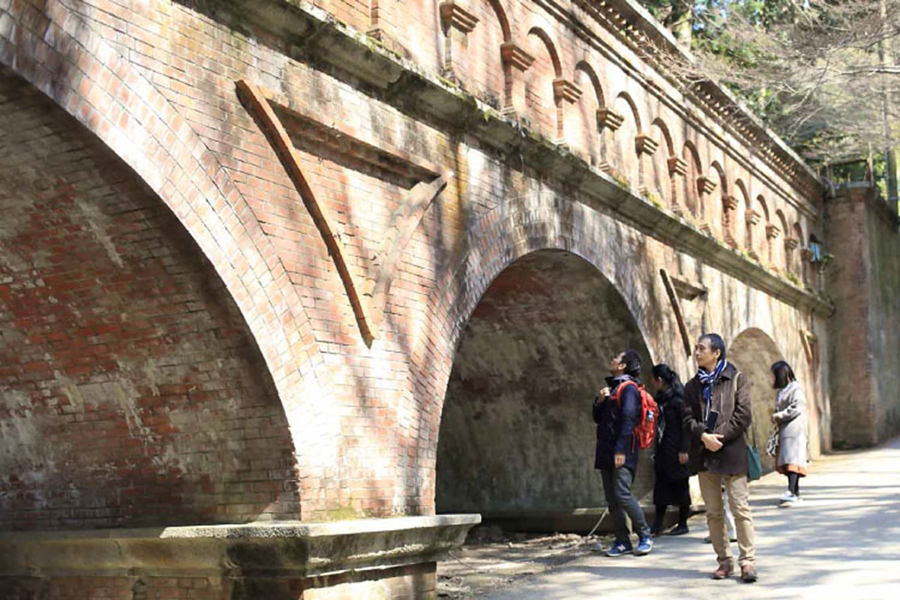 明治時代の赤レンガ造りの水路閣と見上げる観光客