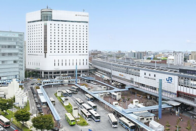 青空の下で高層ビルが立ち並ぶ都市の風景が広がっています。